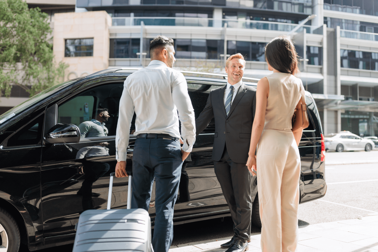 Car Australia chauffeur smiling while holding car door for passengers